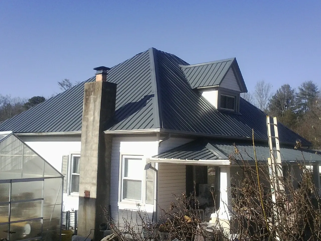 Dark blue standing seam metal roof on a white farmhouse with dormer — Slate & Tile Roof Repair by Roofing Brothers in Falkner