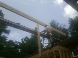 Carpenter setting a ridge beam over a new addition frame — Ice Dam Removal by Roofing Brothers in Falkner