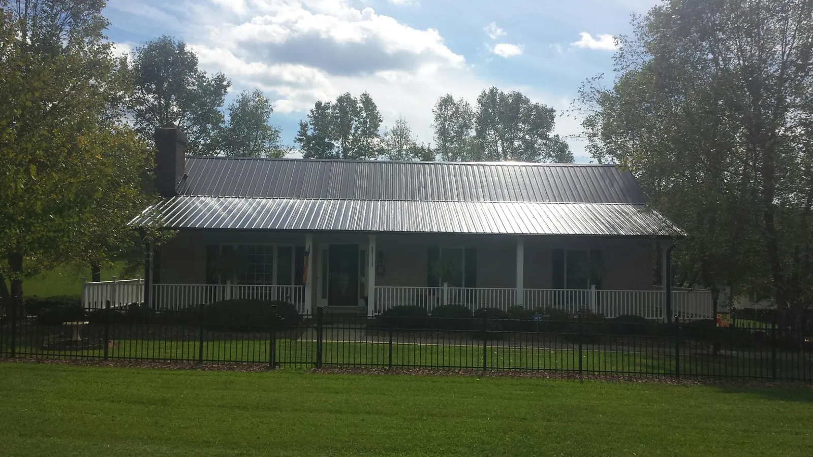 Gray metal roof on a brick ranch with a full width front porch — Gutter Guard Installation work by our crew in Falkner