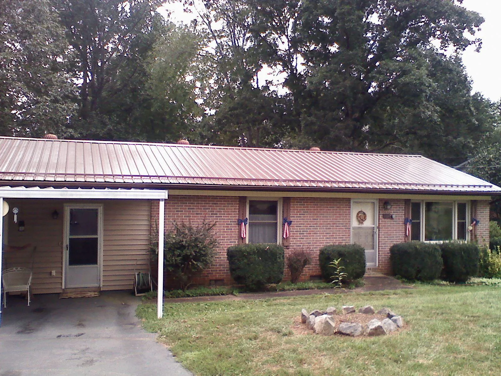Bronze metal roof and carport on a brick ranch home — Roof Repair work by our crew in Falkner