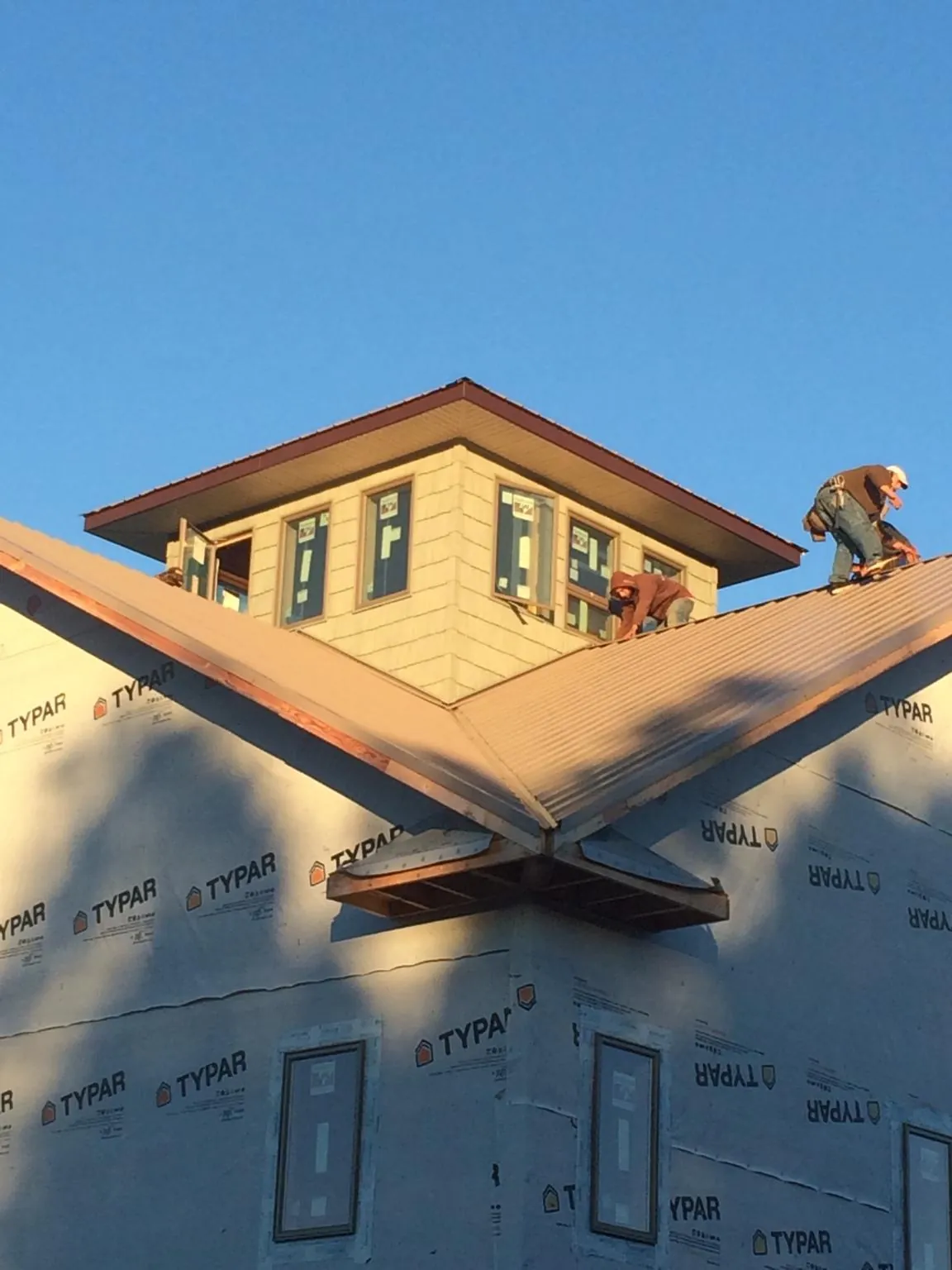 Roofers working around a rooftop cupola on a new metal roof at sunset — Roof Waterproofing in Falkner by Roofing Brothers